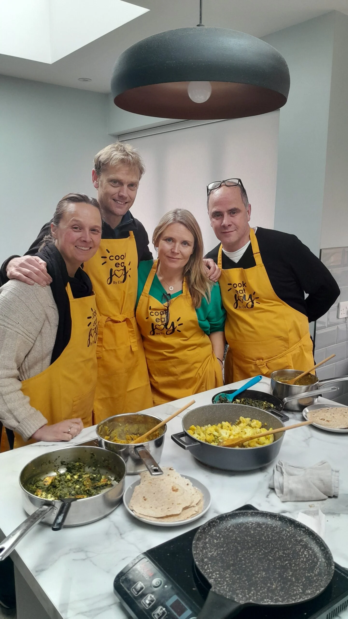 Group workshop attendees in yellow aprons cooking together