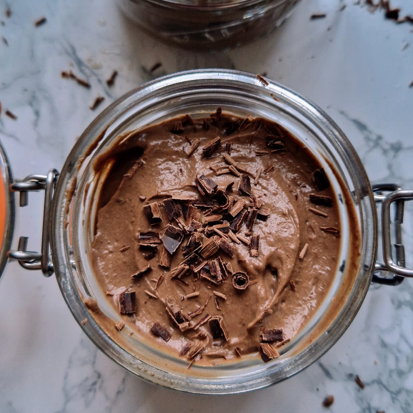 A jar of chocolate mousse topped with dark chocolate shavings.
